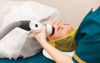 woman laying down receiving laser hair removal wearing a yellow hairnet