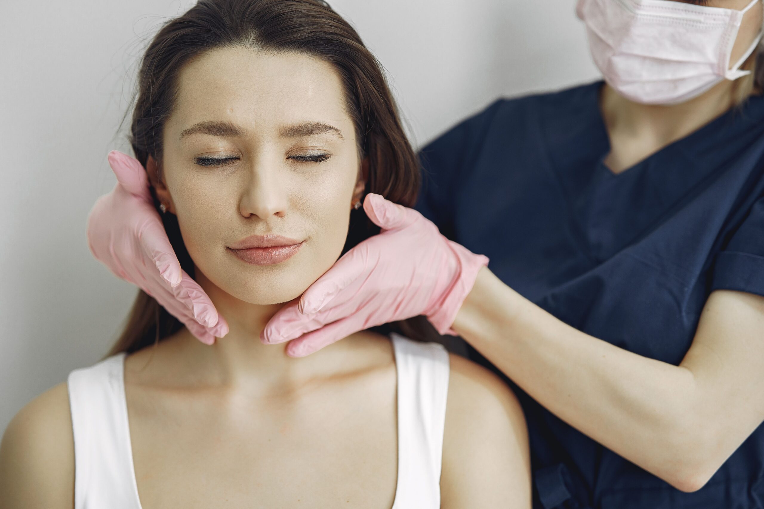 med spa treatment with a woman's face and esthetician wearing pink gloves